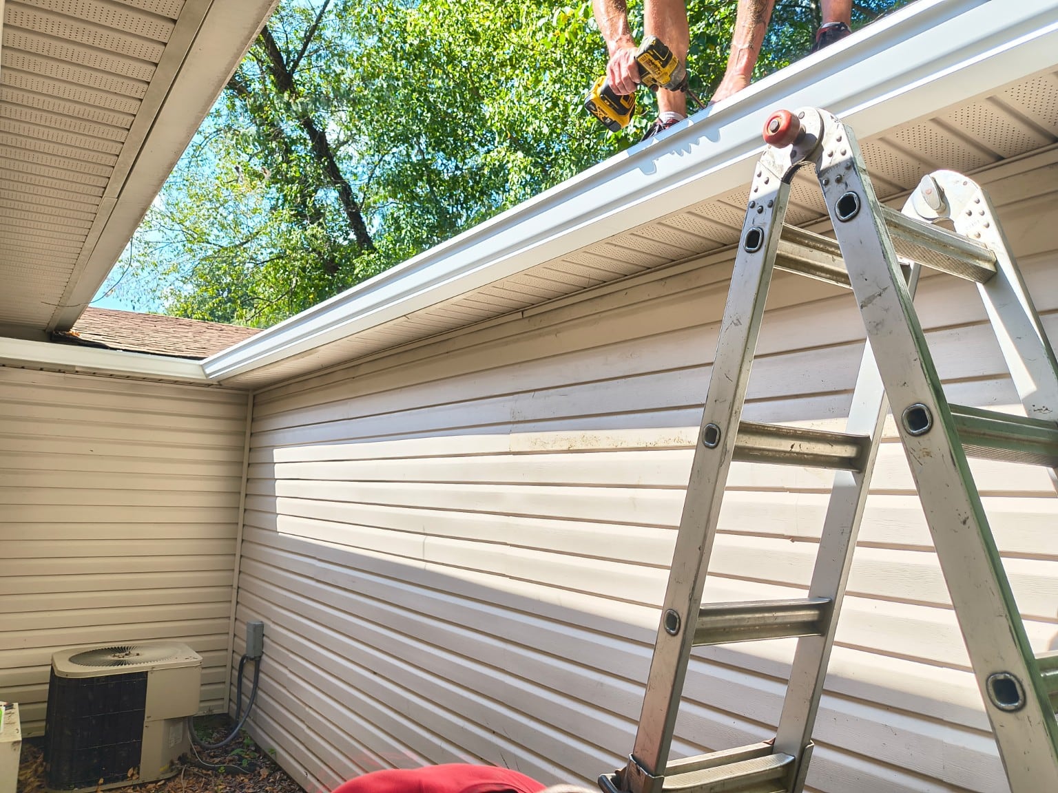 Work being carried out along a white gutter at the roof edge.